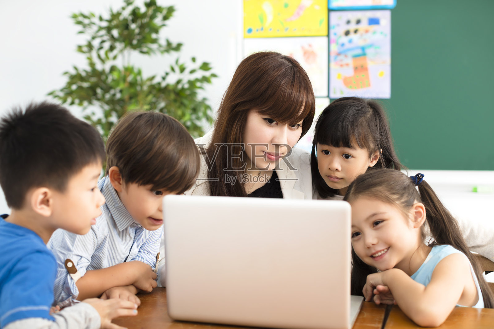 孩子们在看笔记本电脑，老师在旁边照片摄影图片