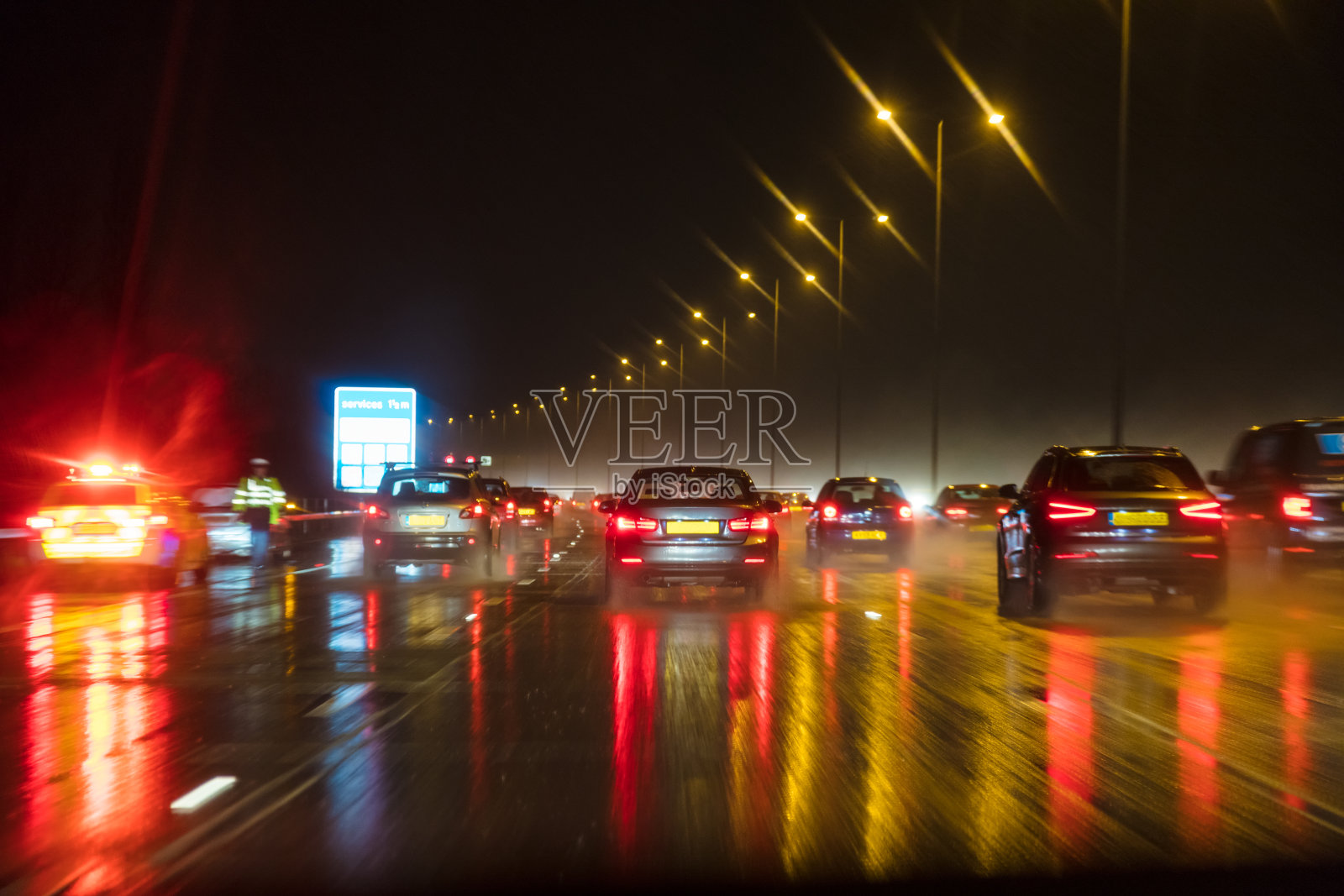 运动模糊的照片，交通在夜晚在雨中在英国高速公路上与警察和汽车照片摄影图片