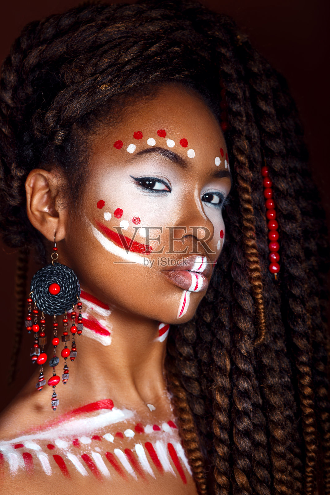 非洲风格的女人。迷人的年轻女子在民族珠宝。一个女人的近距离肖像与一个涂抹的脸。创意的妆容和明亮的风格。照片摄影图片