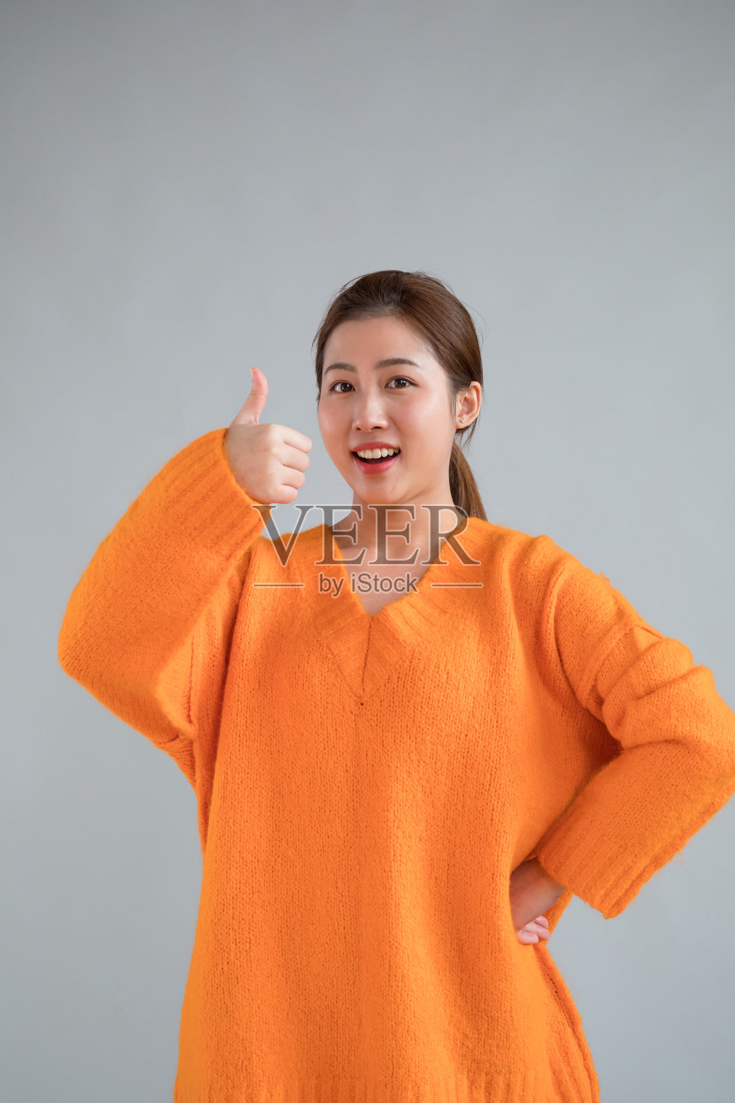 兴奋的亚洲女孩竖起大拇指，在工作室拍照照片摄影图片