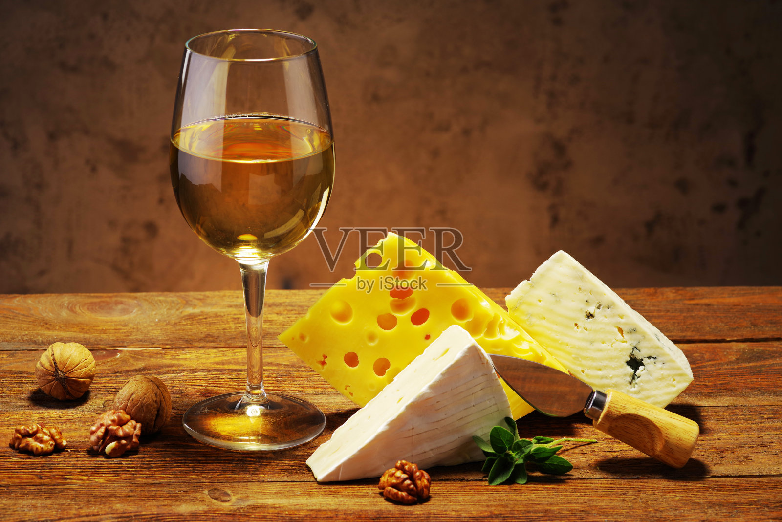 奶酪和葡萄酒装在玻璃杯里放在木板上。照片摄影图片