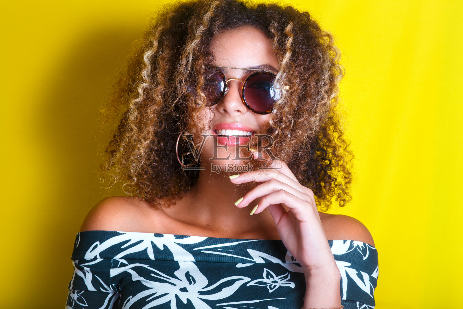 室内的肖像，一个年轻的非洲裔美国妇女戴着太阳镜。黄色背景。的生活方式。休闲装照片摄影图片