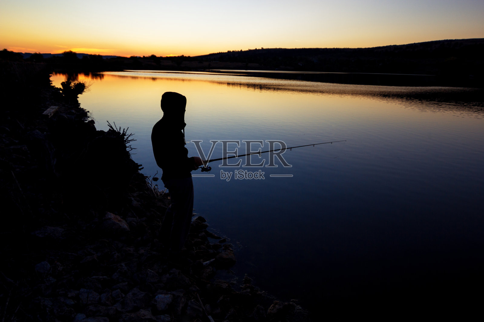 日落时分在海边钓鱼。照片摄影图片
