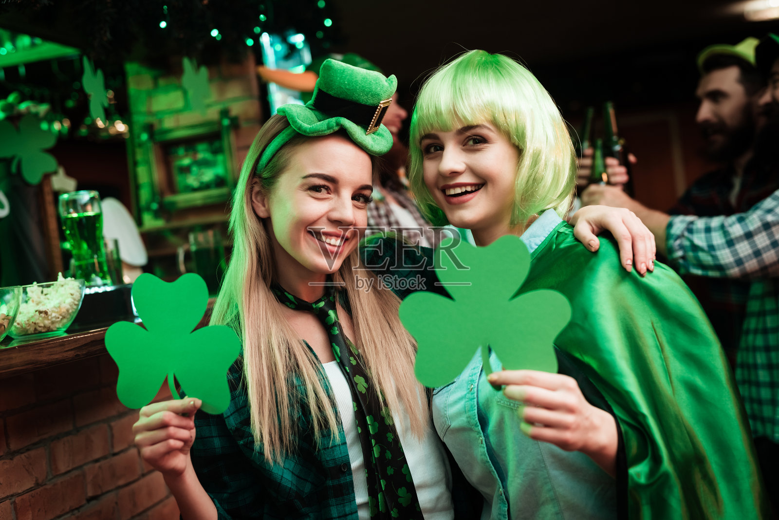 两个戴着假发和帽子的女孩被拍到在一个酒吧里。照片摄影图片