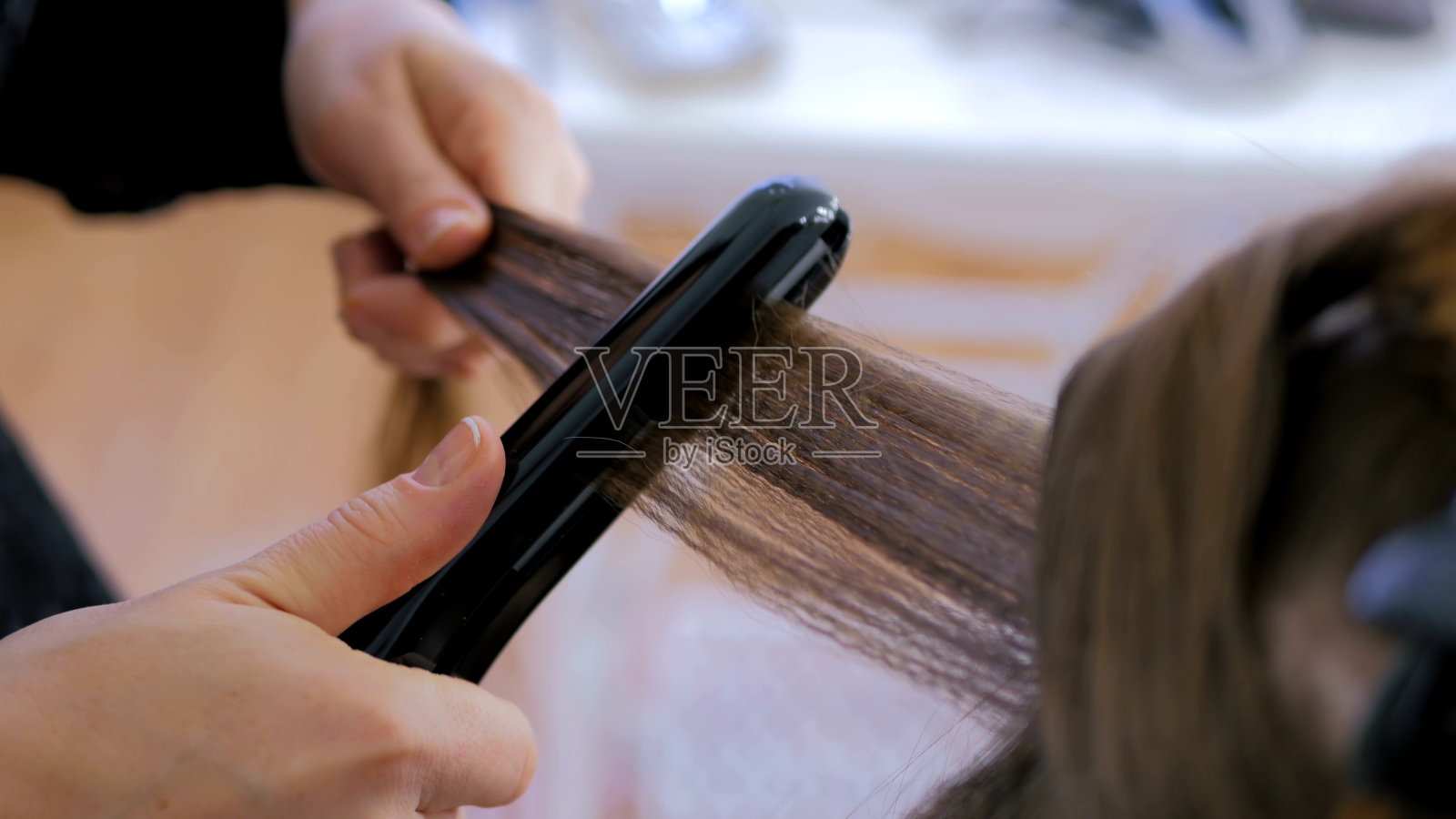 发型师在发廊对顾客的长发使用直发器照片摄影图片