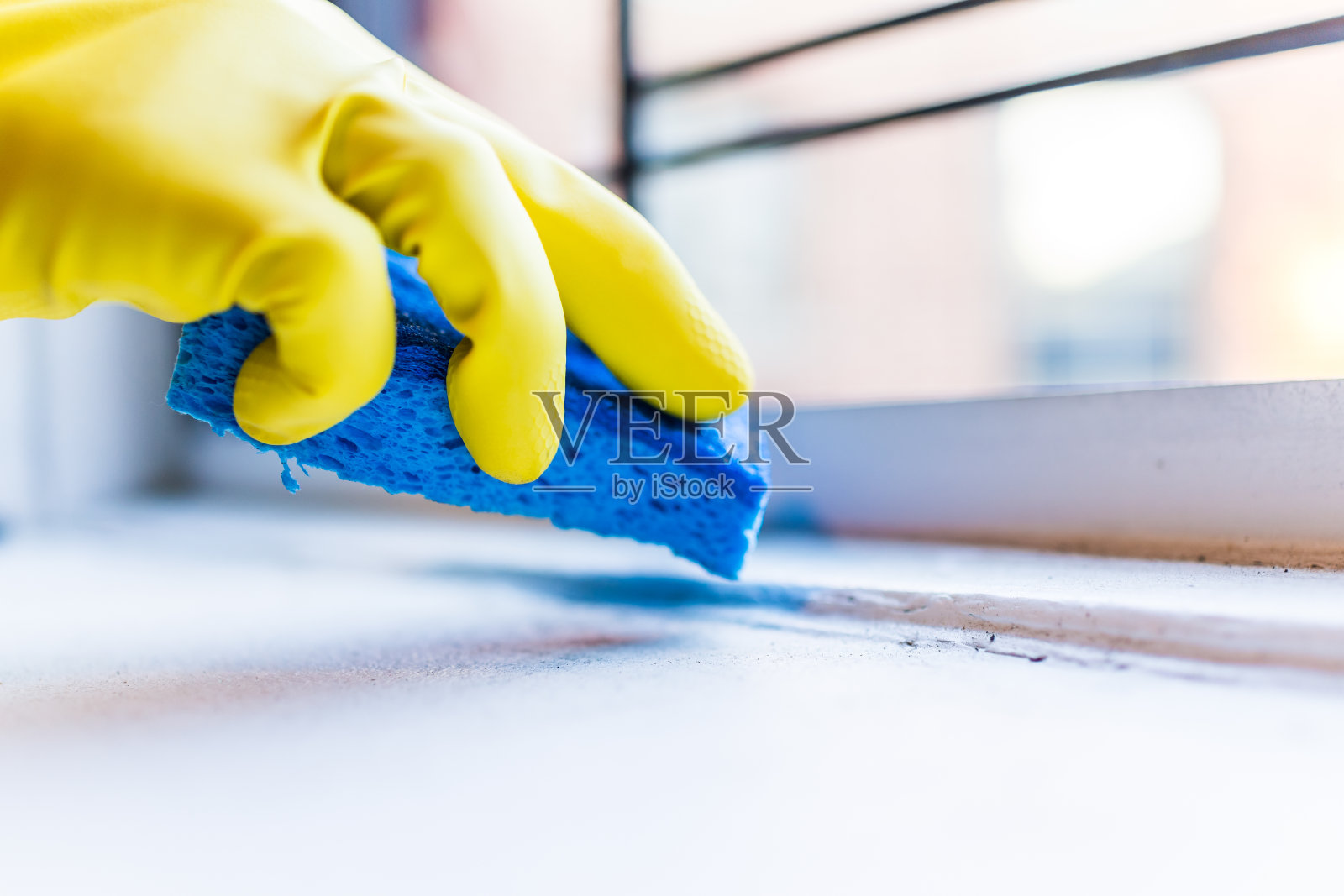 黄色手套手清洁灰尘，窗台上的污垢与蓝色海绵在纽约市的城市公寓窗户照片摄影图片