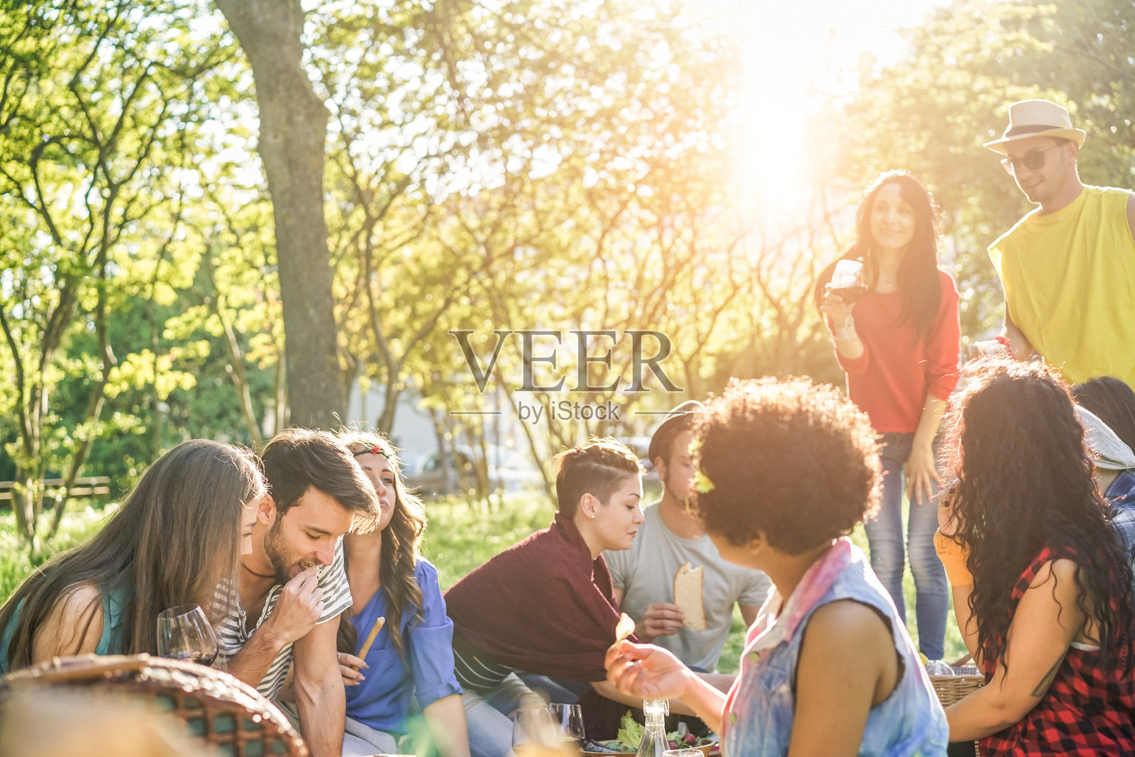 快乐的朋友吃和喝红酒在户外野餐聚会-年轻时尚的人一起在夏季晚餐的乐趣-品味，友谊和青年的生活方式概念-集中在两个离开的家伙照片摄影图片