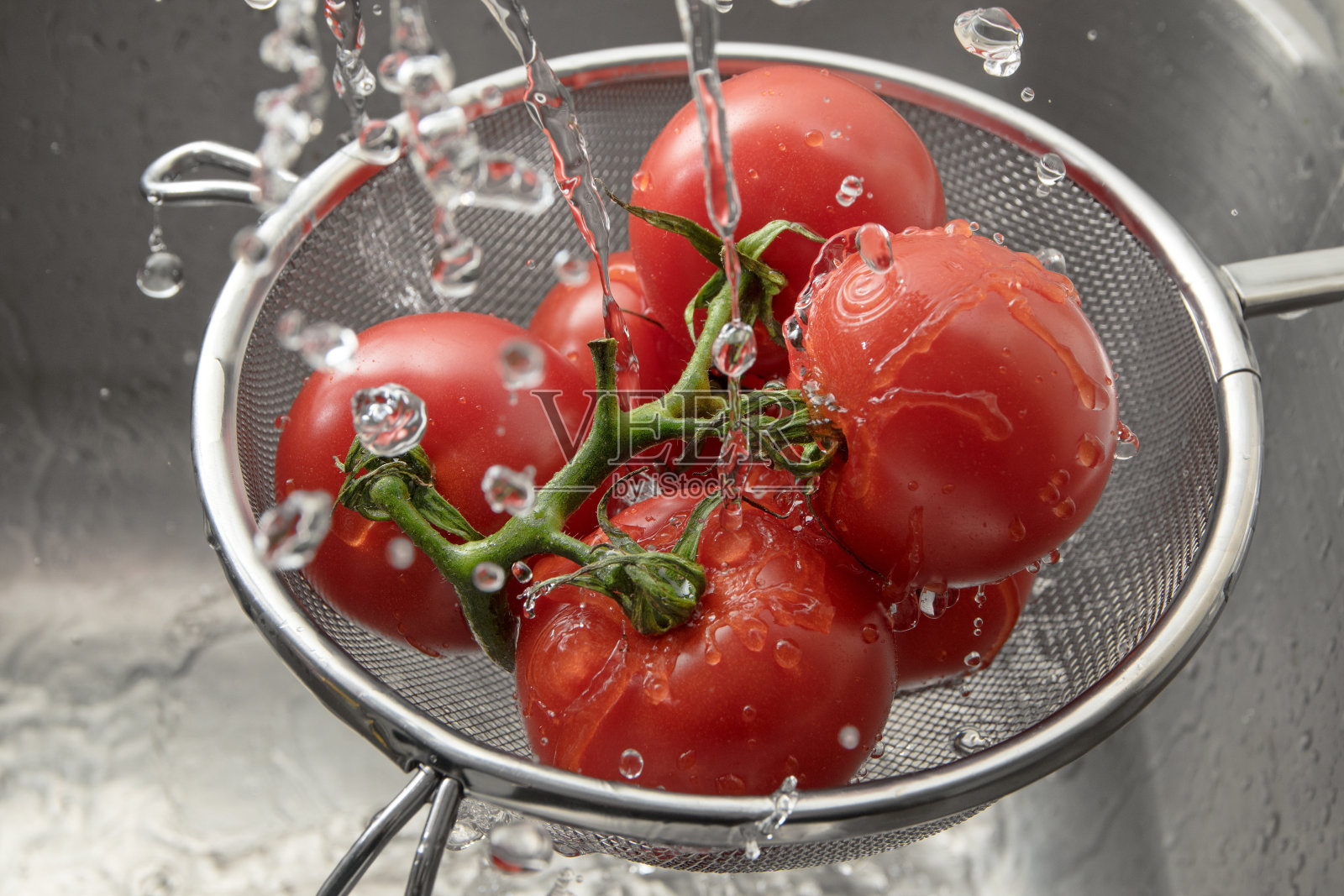 新鲜的西红柿在金属过滤器中的许多水滴中，清洗和准备健康的食物照片摄影图片
