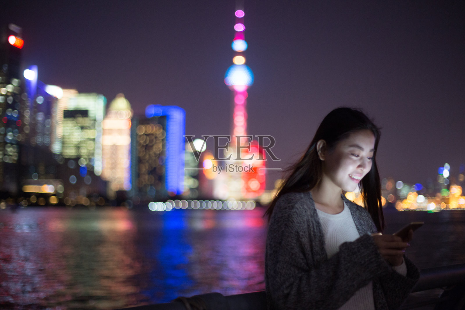 年轻的亚洲妇女在现代城市玩手机照片摄影图片