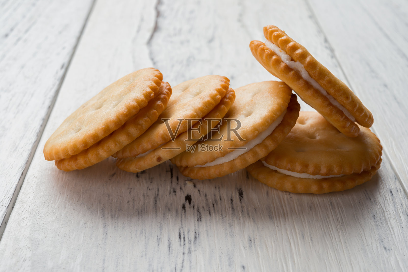 三明治饼干，白色的奶油馅，白色的木头背景照片摄影图片