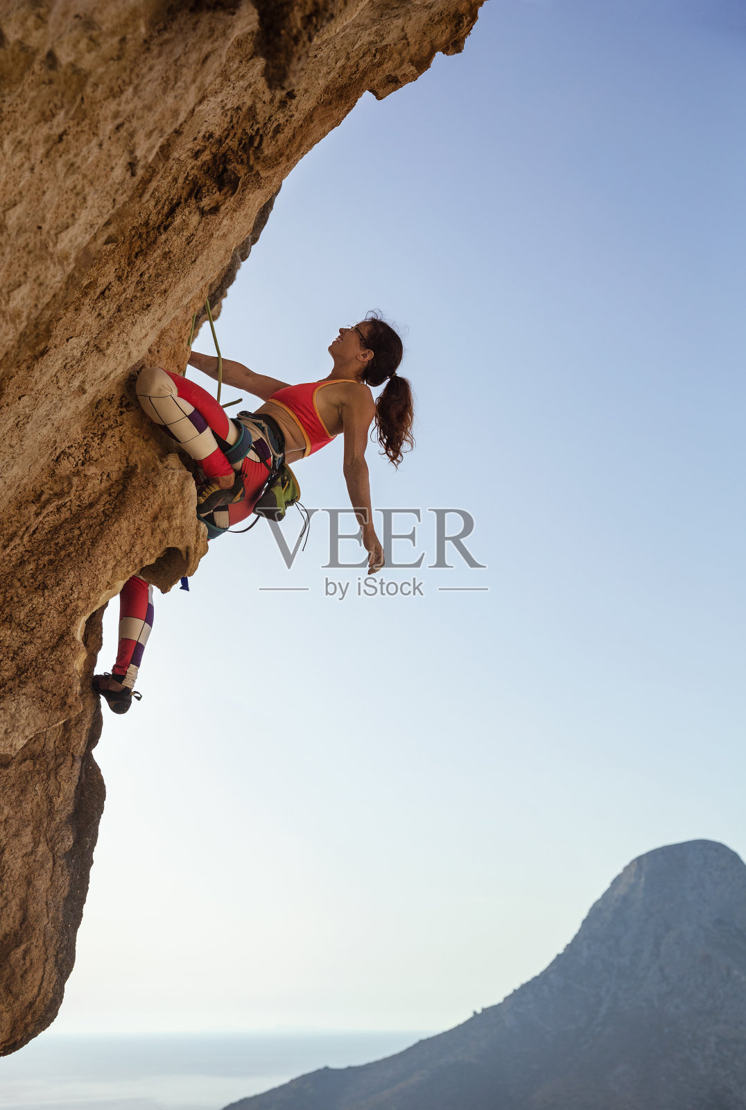 一位女性攀岩者正仰望着充满挑战的路线照片摄影图片