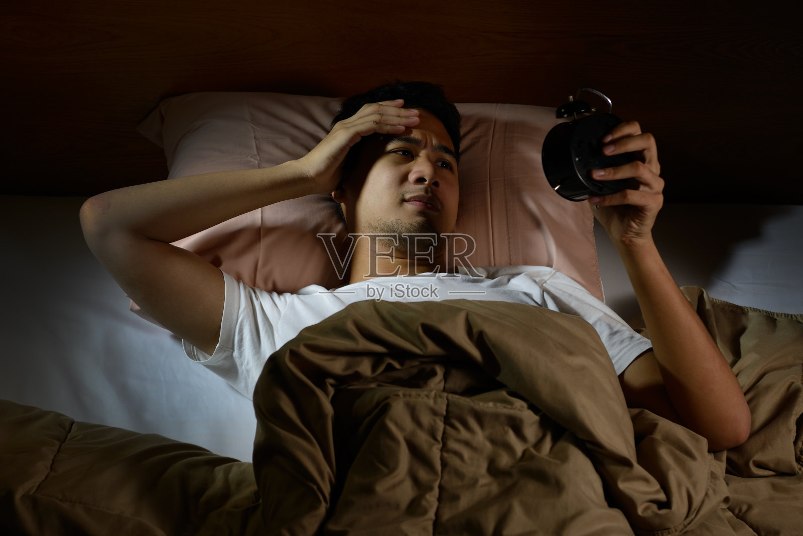 抑郁症患者躺在床上看着闹钟，饱受失眠之苦照片摄影图片