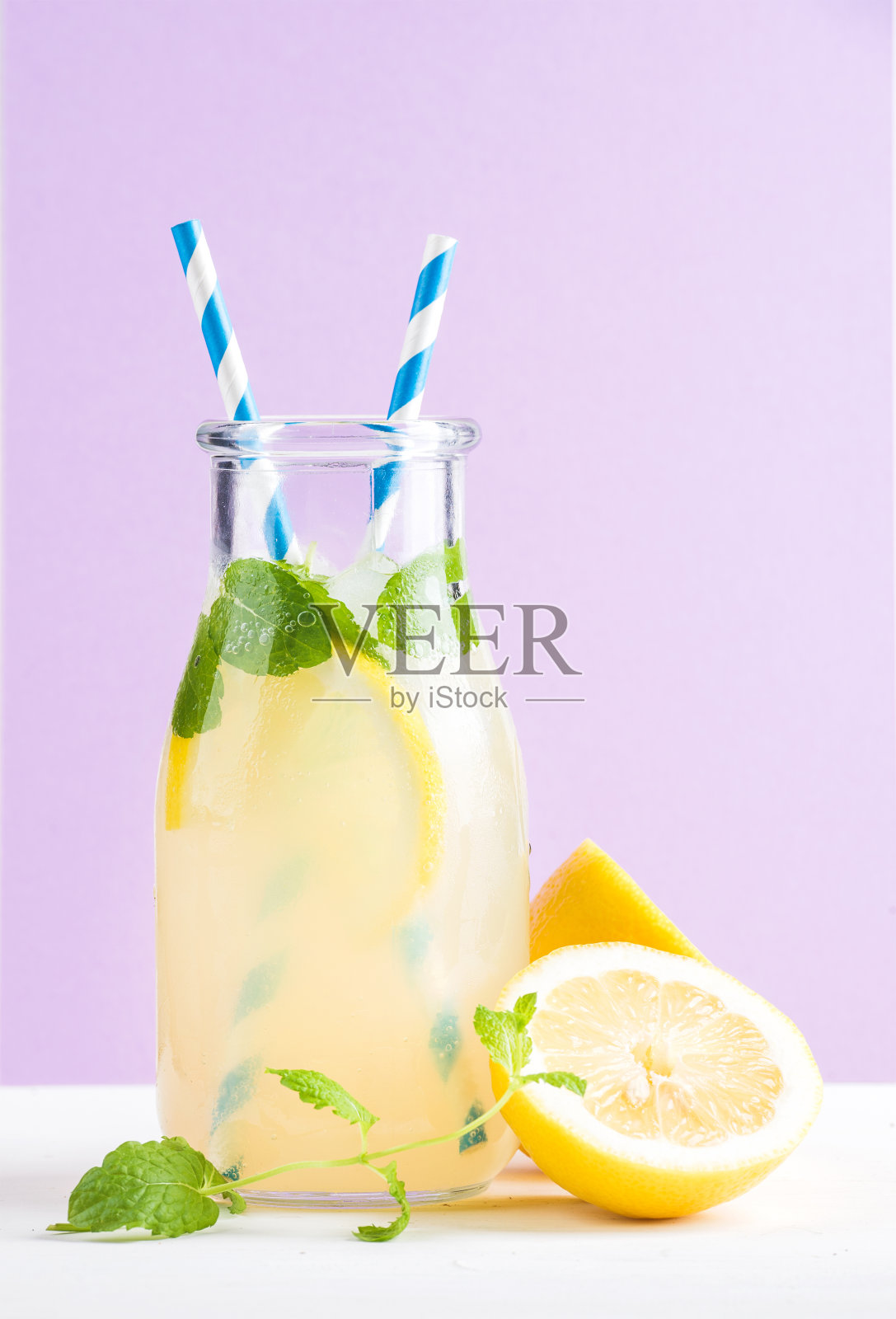 瓶自制柠檬水，薄荷，冰，柠檬，纸吸管和淡紫色背景照片摄影图片