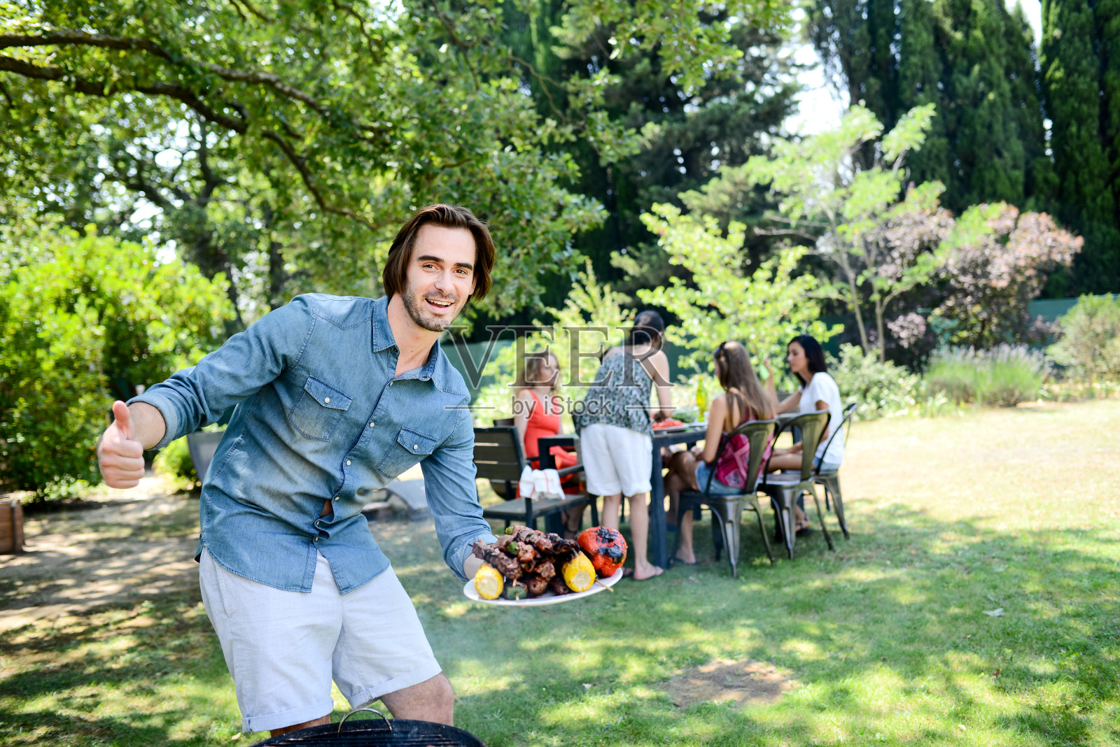 暑假期间，一帅哥在花园户外烧烤聚会上做饭照片摄影图片