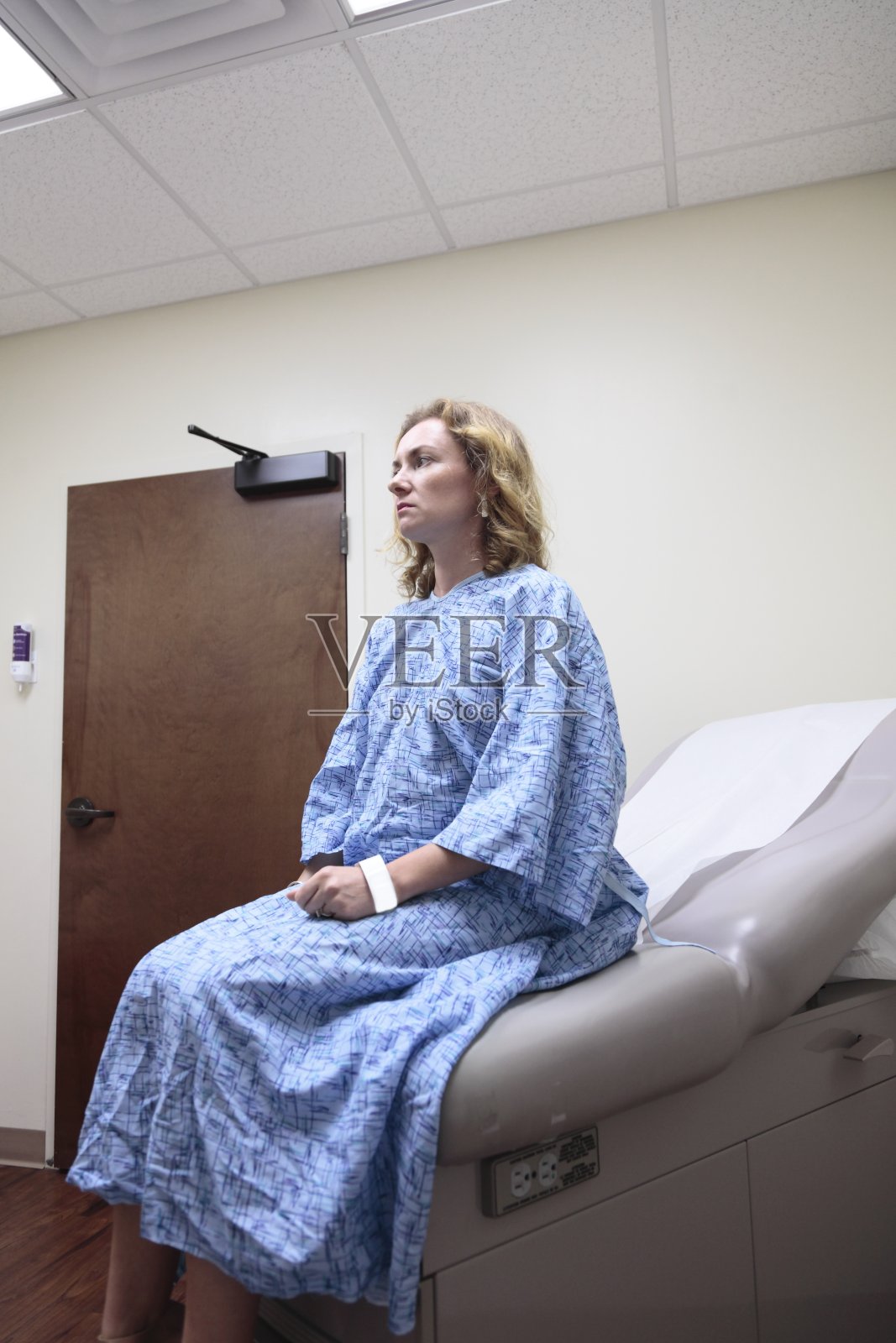 在医院的年轻女子坐在九楼的病床上。照片摄影图片