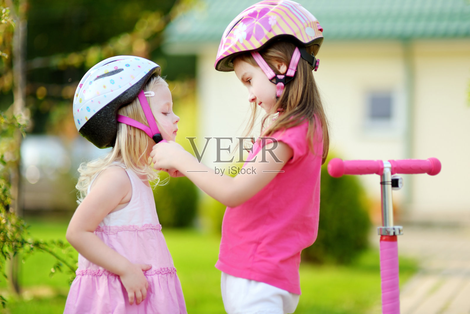 小女孩帮她姐姐戴上头盔照片摄影图片