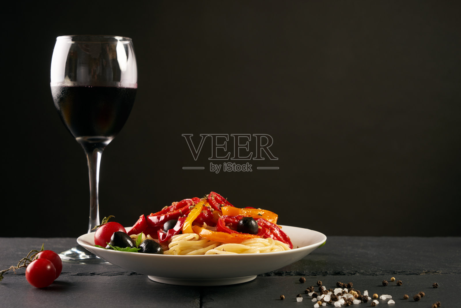 配帕尔马干酪、罗勒橄榄、paprica和西红柿的意大利面，放在白色盘子上，在黑色的背景上单独复制空间。照片摄影图片