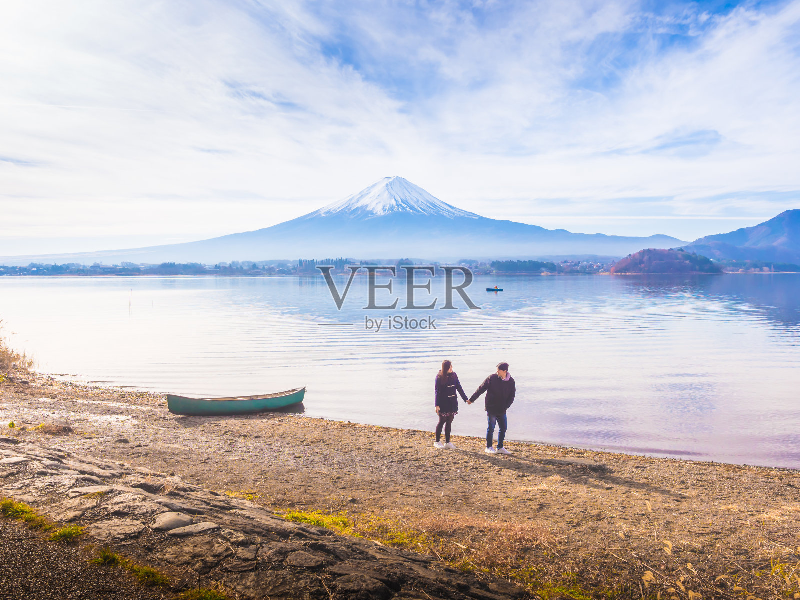 亚洲夫妇旅行者30多岁到40多岁，男孩与女友的手牵手走在河口湖畔的地面上，在早上的时间与富士山的背景照片摄影图片