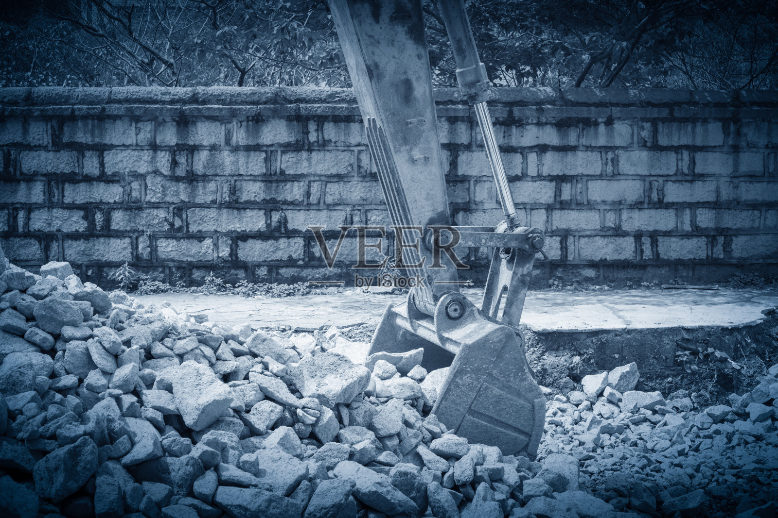 重型挖掘机用铁铲站在有石头的小山上照片摄影图片