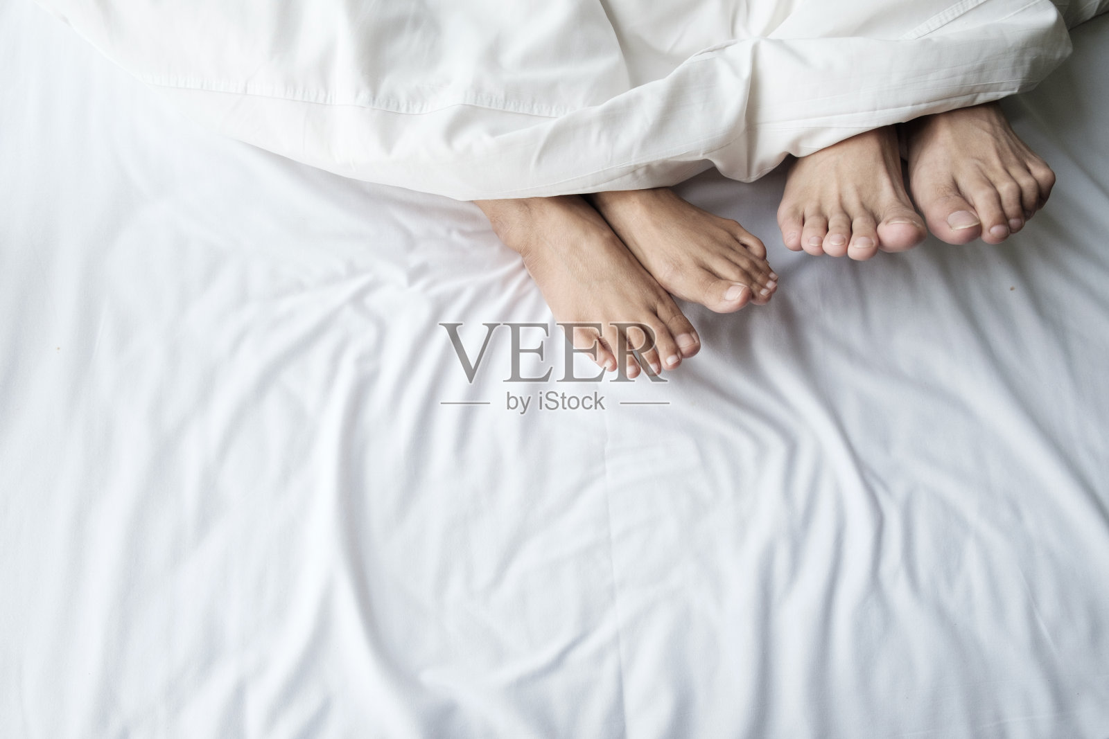 并排睡的一对夫妻的脚。照片摄影图片