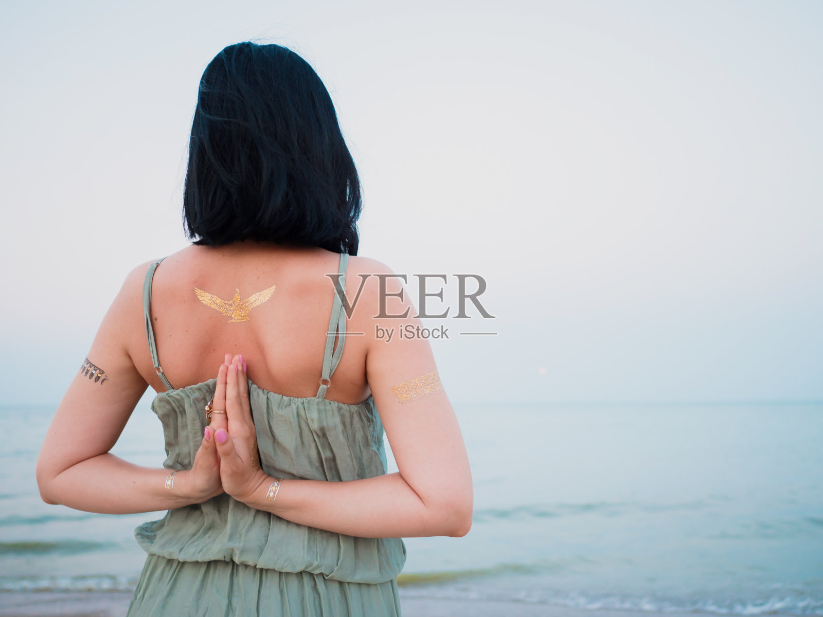 银色和金色的闪光纹身在女性的手越过海洋或海洋背景。女人练习瑜伽。合十礼照片摄影图片