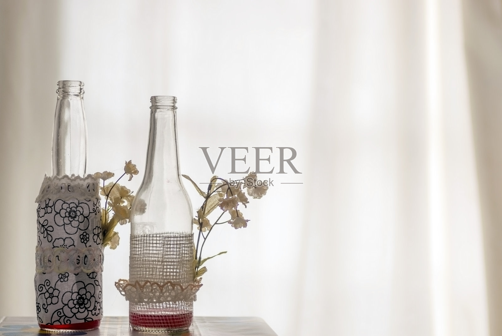 装饰的玻璃瓶在一个柔和的背光背景，与小花朵在一边照片摄影图片