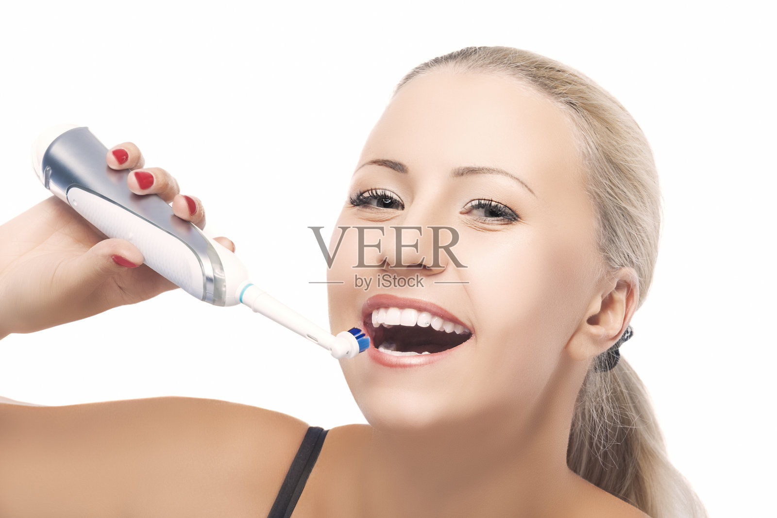 牙齿健康的概念:金发白种人用电动牙刷刷牙。孤立在纯白色背景。照片摄影图片