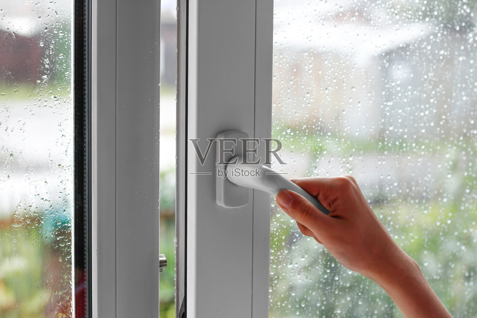 一个女人的手用水珠打开窗户。关闭窗口。在雨天。特写镜头照片摄影图片