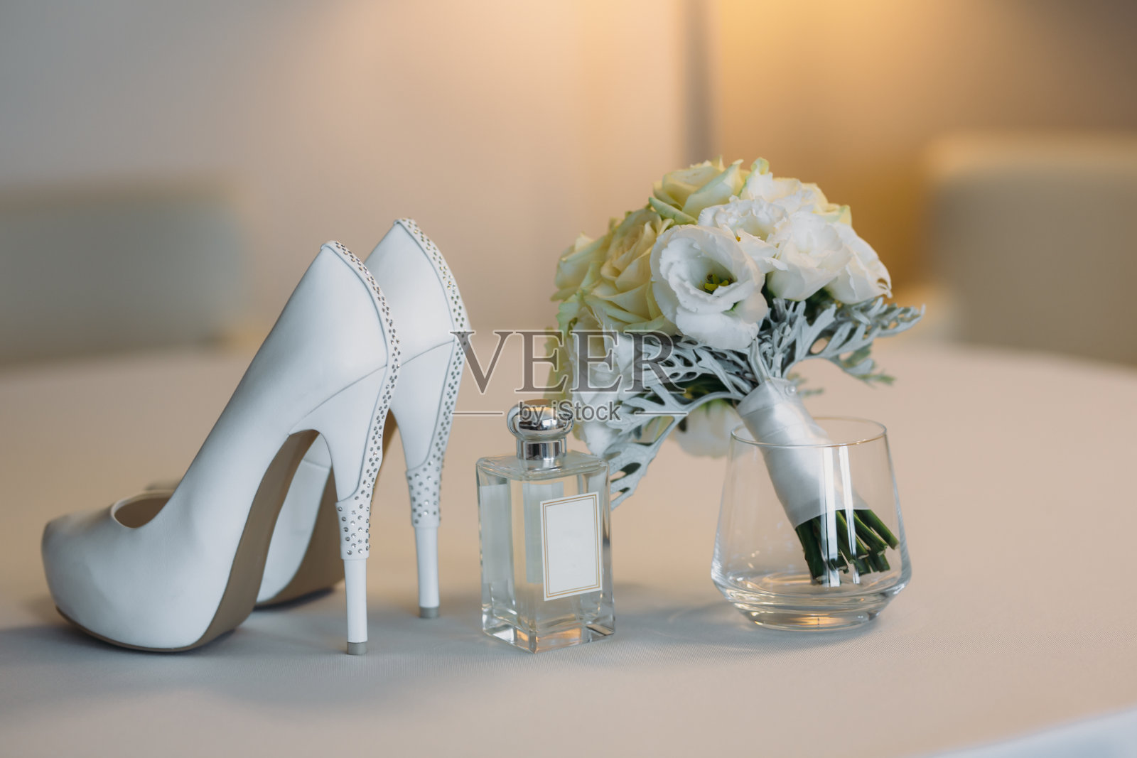 白色的椅子上放着新娘的饰品，有花、香水鞋、花束。服装的概念照片摄影图片
