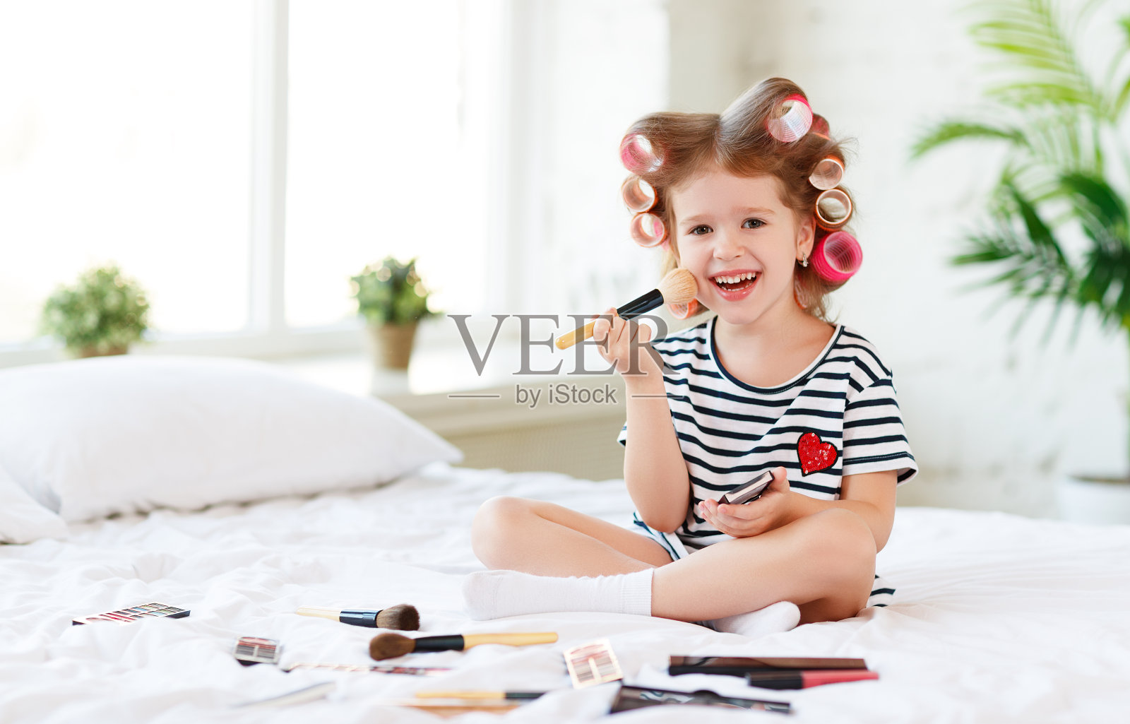 漂亮有趣的小女孩在化妆，在床上笑照片摄影图片