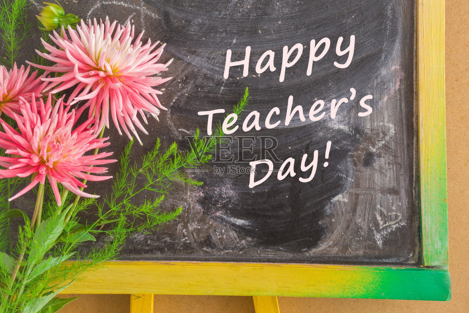 教师节贺卡与新鲜的紫菀花。在学校的黑板上写上教师节快乐。照片摄影图片
