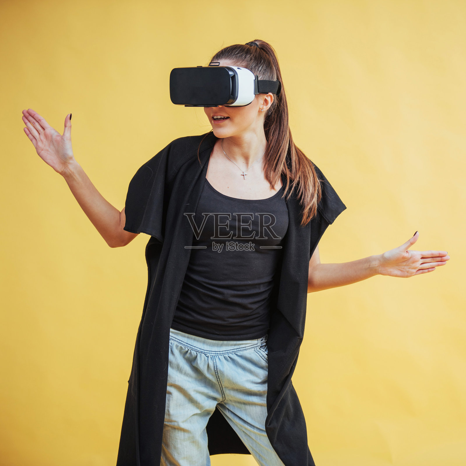 在演播室背景的快乐女人获得使用VR-glasses虚拟现实耳机的体验照片摄影图片