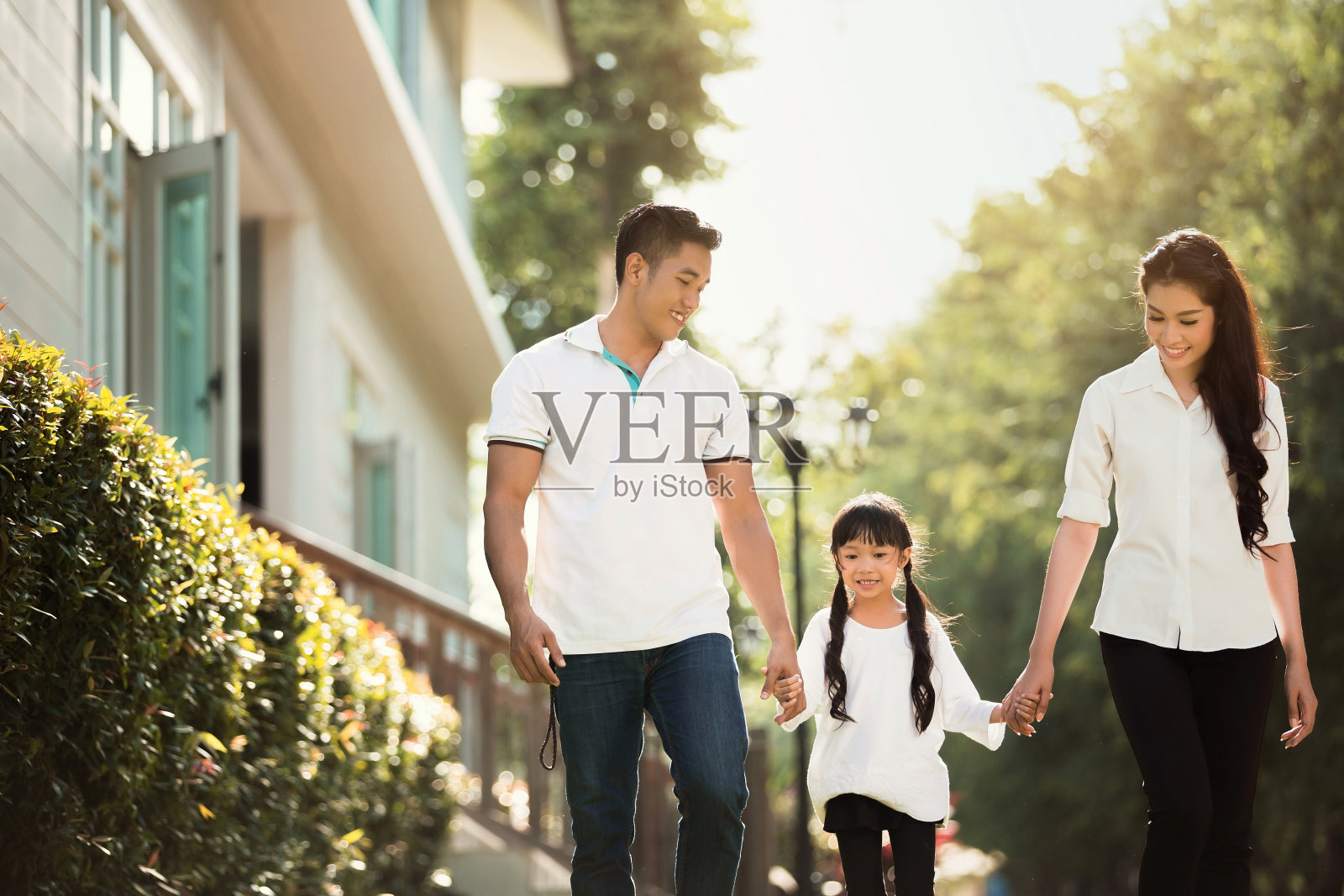亚洲家庭正在走出房子。父母和孩子们手牵手一起快乐地走着照片摄影图片