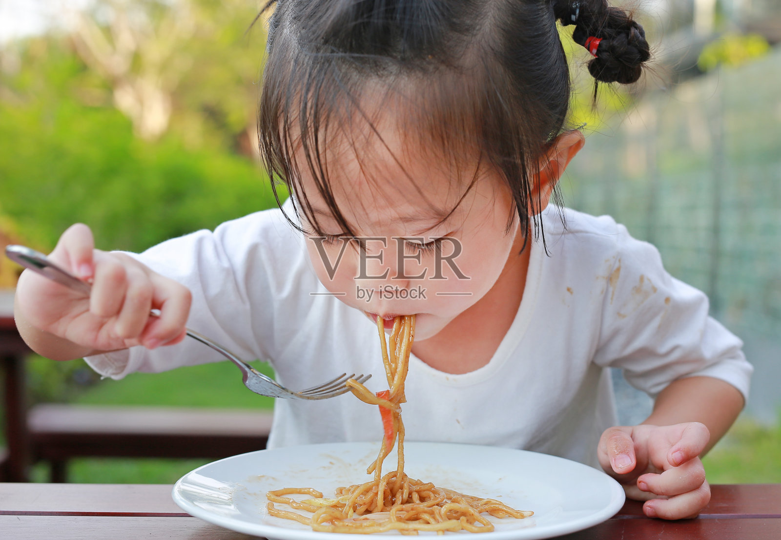 小女孩在吃日式烧面条。照片摄影图片