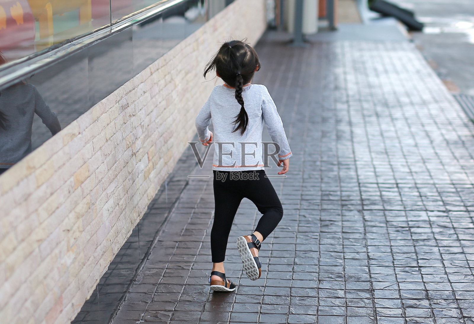 小女孩在人行道上奔跑的背影。照片摄影图片