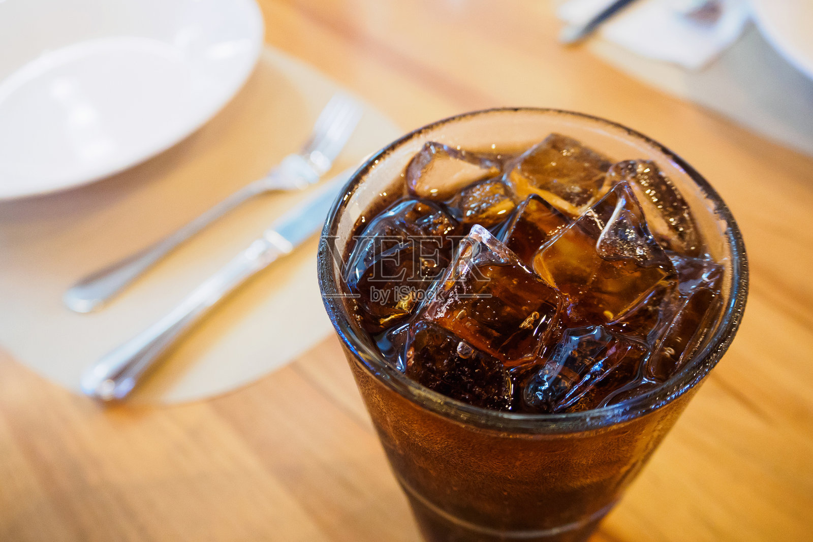 在餐厅背景的木桌上有冰的可乐杯软饮料照片摄影图片