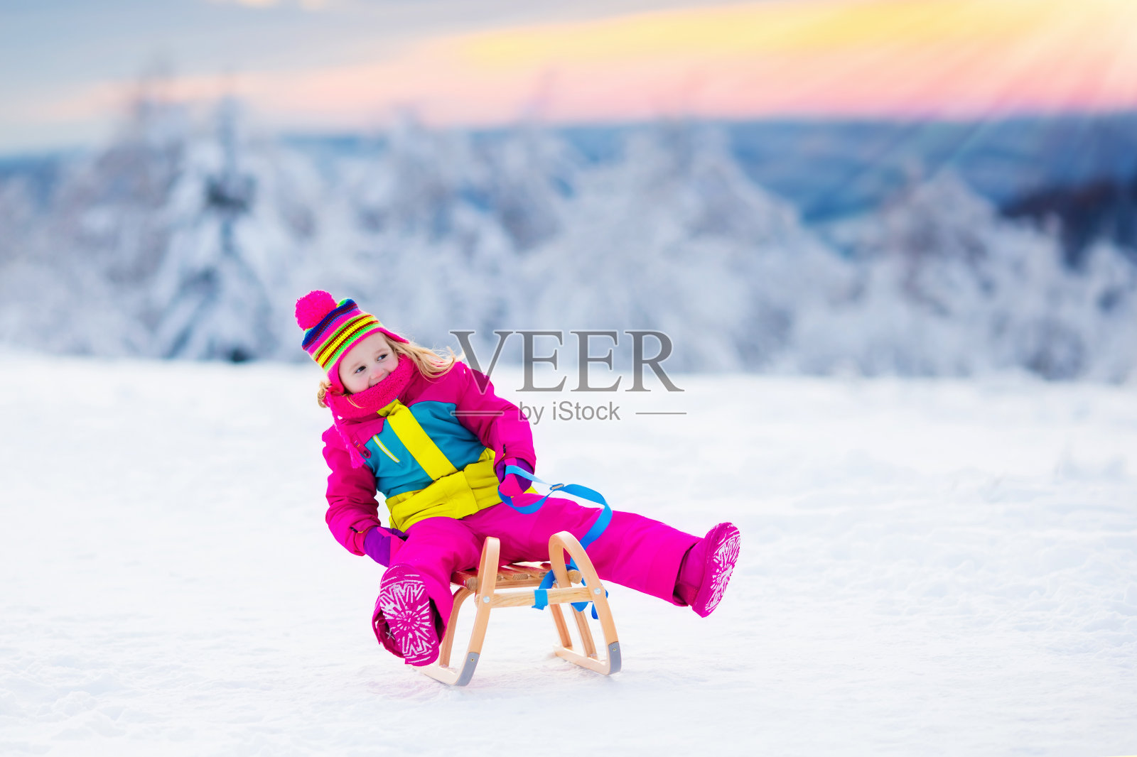 孩子们在冬季公园的雪地上玩雪橇照片摄影图片