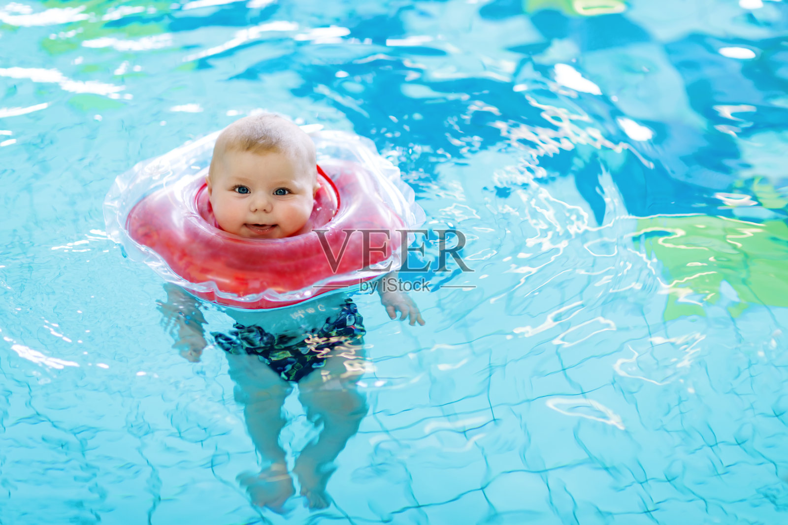 可爱的小婴儿在室内游泳池里用游泳圈学习游泳照片摄影图片