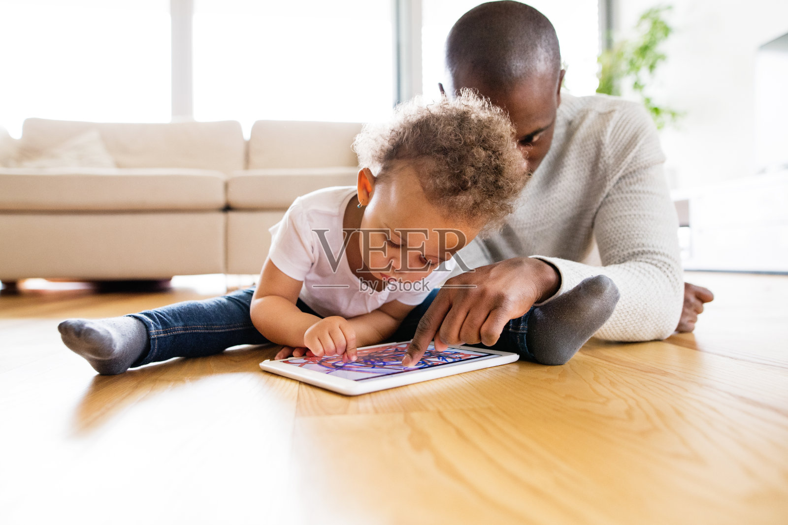 非裔美国父亲带着家里有平板电脑的小女儿。照片摄影图片