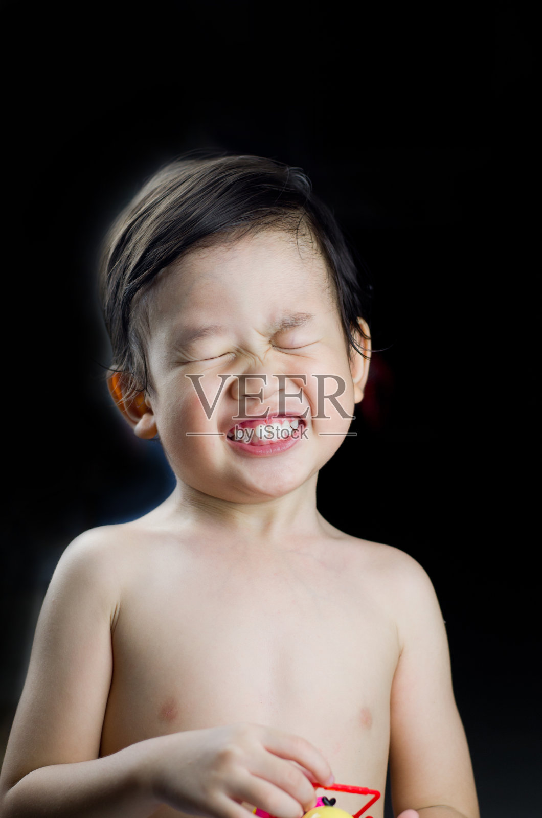 表情可爱的亚洲婴儿微笑或快乐的婴儿脸与玩具在黑色的背景，童年概念，幸福的家庭概念照片摄影图片