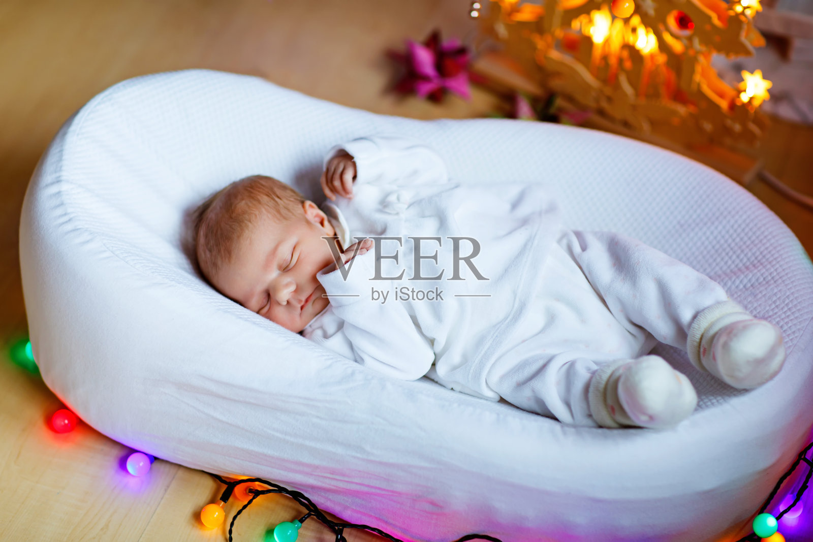 一个星期大的新生女婴睡在圣诞树旁照片摄影图片