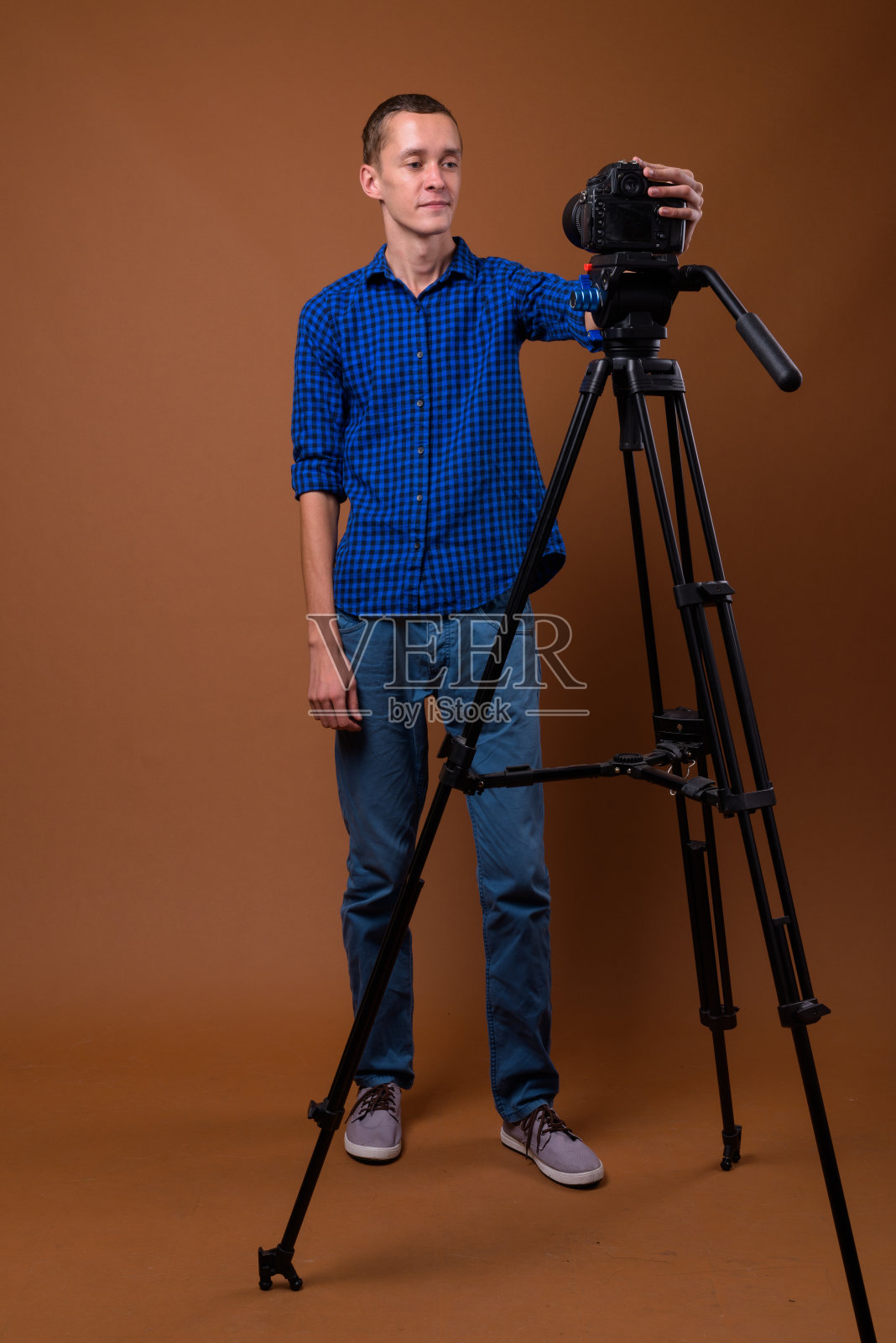 这是一个年轻人穿着蓝色格子衬衫准备在彩色背景下拍摄的视频照片摄影图片