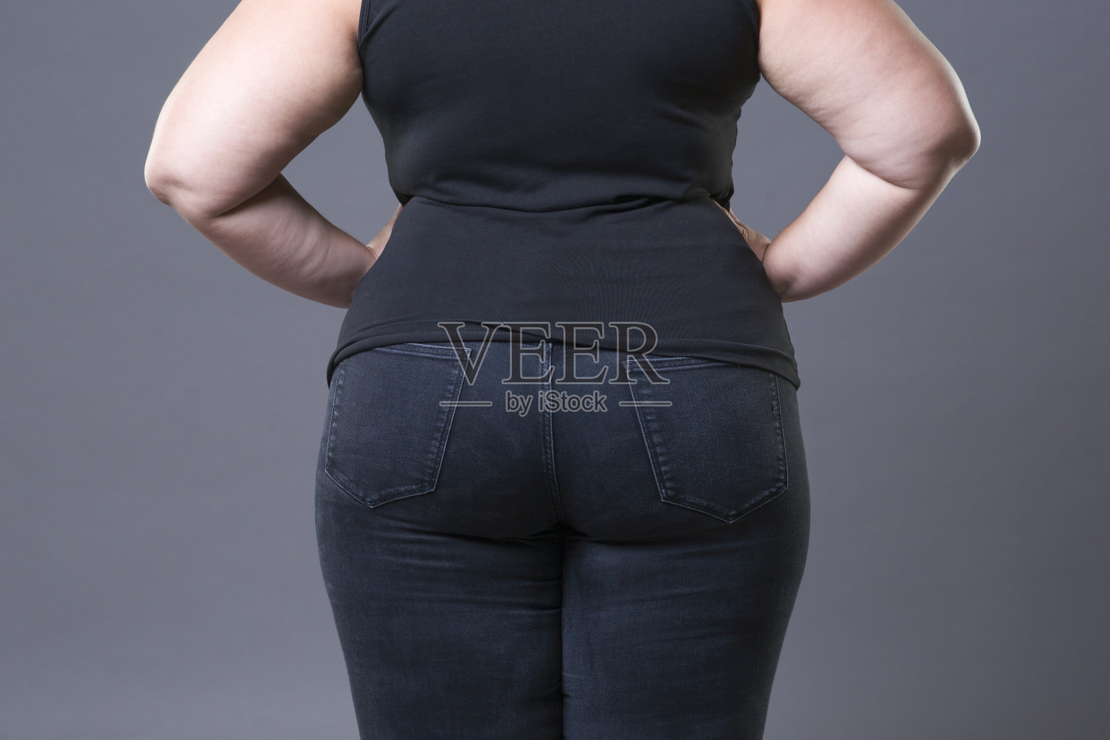 胖女人臀部黑牛仔裤，超重女人身体特写照片摄影图片