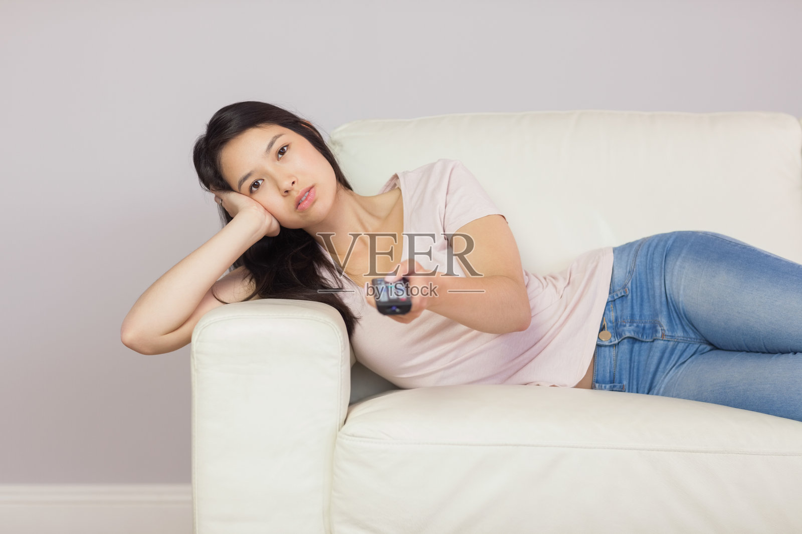 无聊的亚洲女孩躺在沙发上看电视照片摄影图片