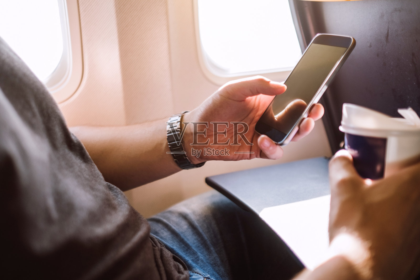 一名年轻人在飞机上用手机发短信照片摄影图片