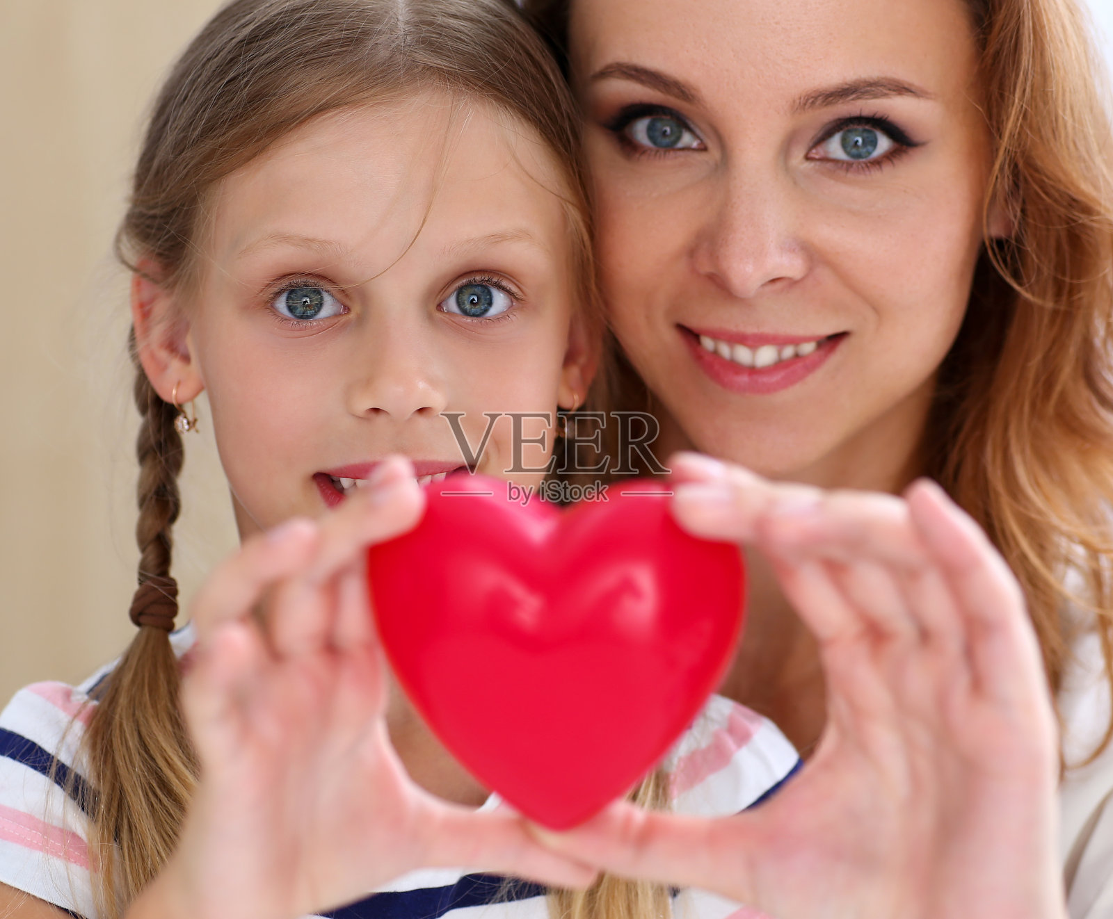 美丽微笑的女人和孩子抱着红色的玩具心照片摄影图片