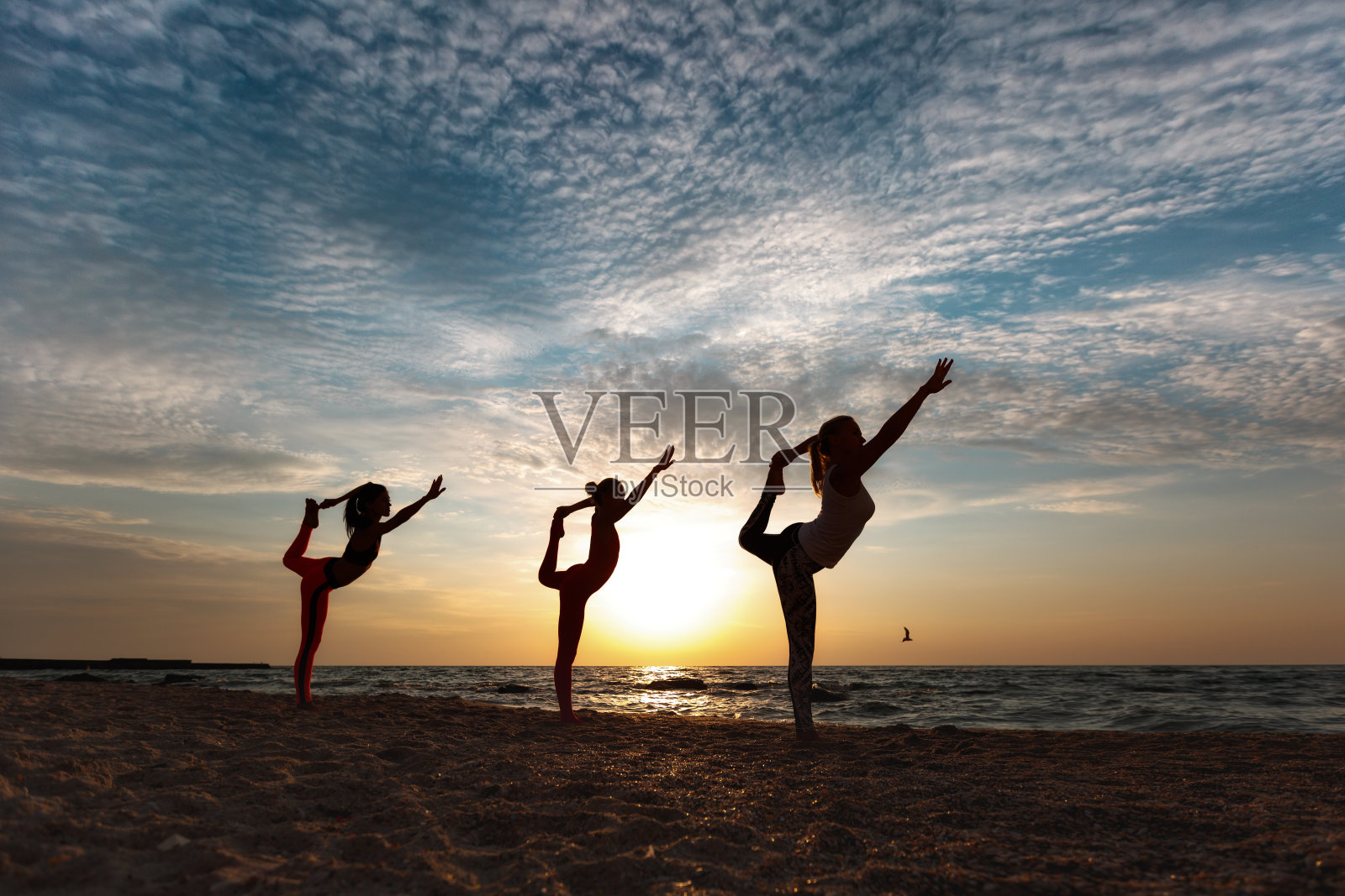 日出时，一群妇女在海边做瑜伽照片摄影图片