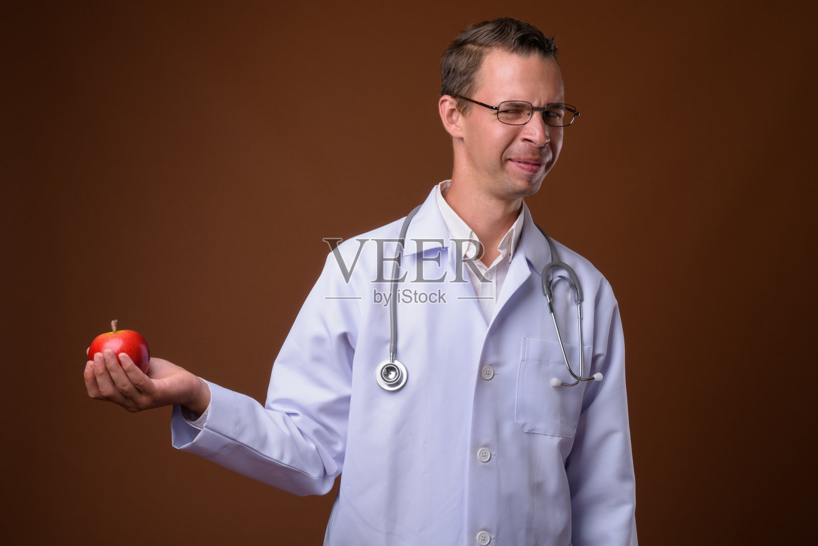 摄影棚里的男医生戴着眼镜，背景是彩色的照片摄影图片