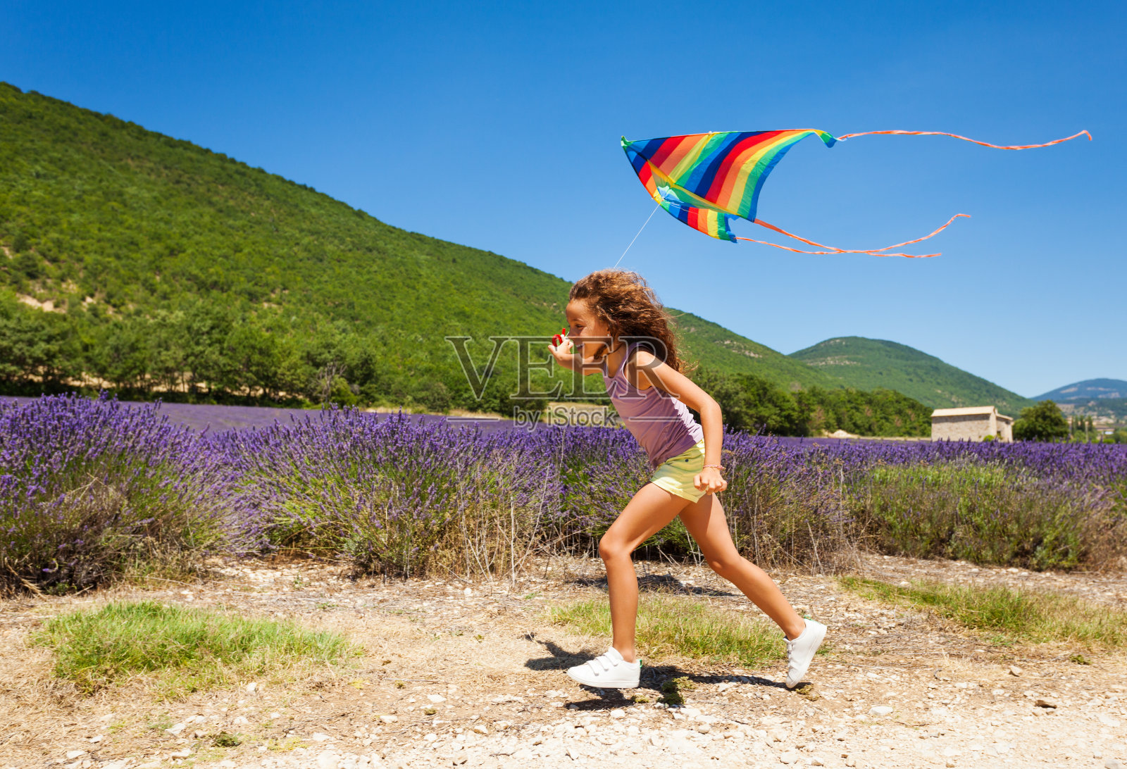 快乐的十多岁的女孩和彩虹风筝跑照片摄影图片