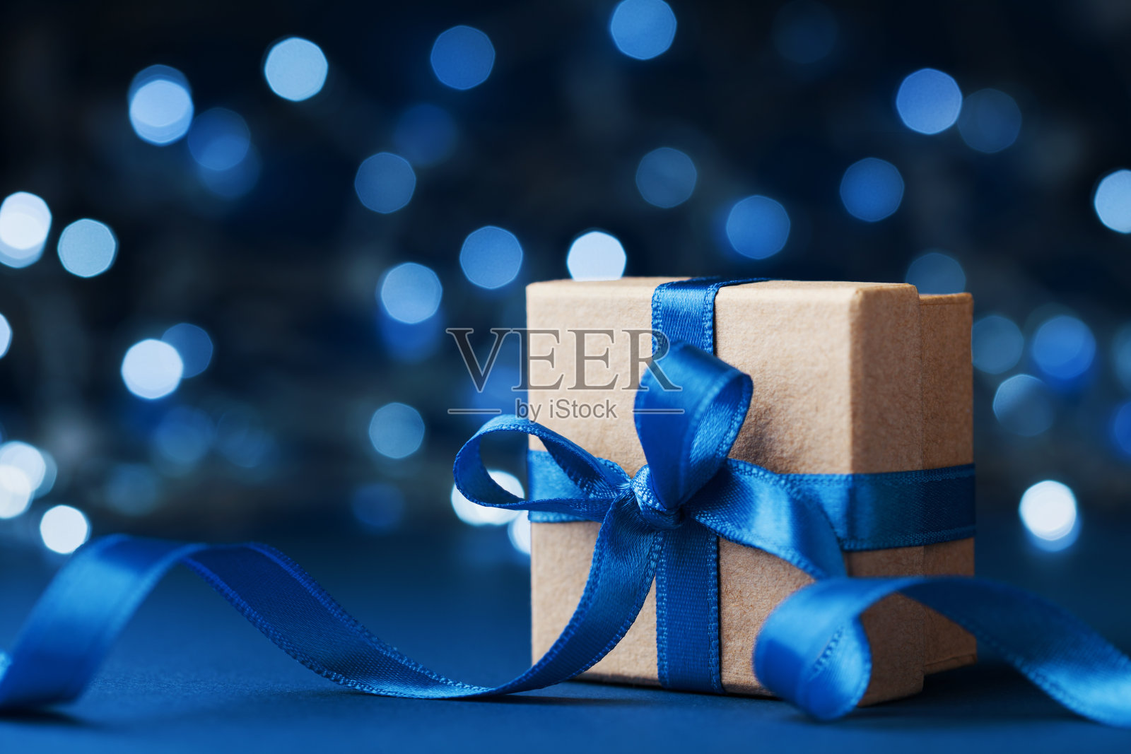 以蓝色散景为背景，配蝴蝶结丝带的节日礼盒或礼品。神奇的圣诞贺卡。照片摄影图片